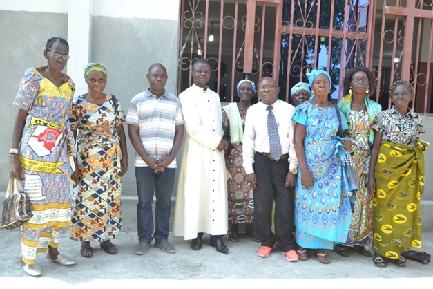Devant l’église paroissiale, le Curé de Christ Sauveur entouré des membres de la Caritas paroissiale et de monsieur Michel Olenga (en cravate)